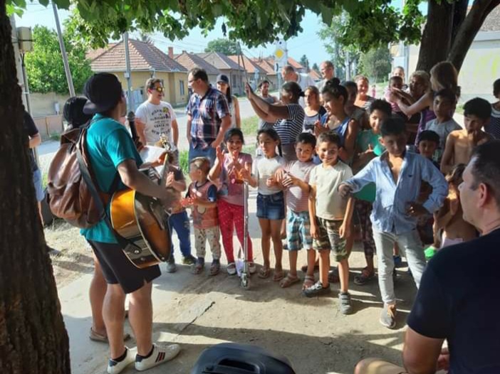A man worshipping with a guitar surrounded by children