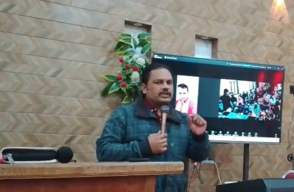 A preacher on stage with Wayne on video link